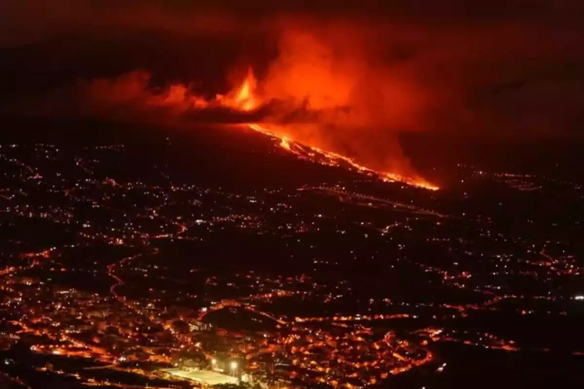 Imagen del volcán en erupción con la ciudad a sus pies de noche