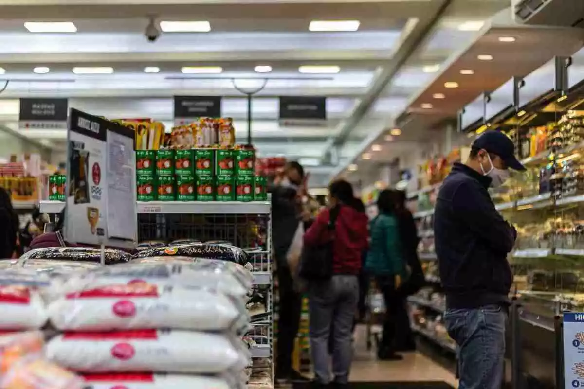 Imagen de un supermercado con gente comprando en su interior