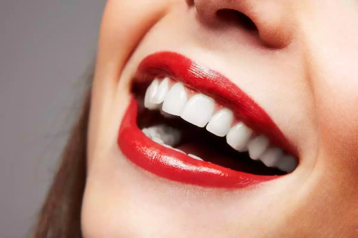 Una mujer con la boca abierta, labios rojos y dientes blancos como la nieve
