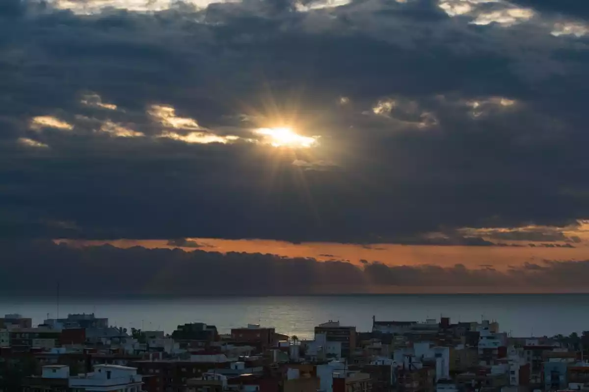 Imagen de una salida de sol entre nubes en Valencia