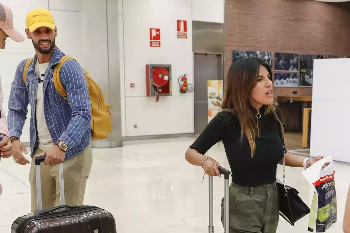 Isa Pantoja y Asraf Benó con maletas en la mano en un andén volviendo de viaje