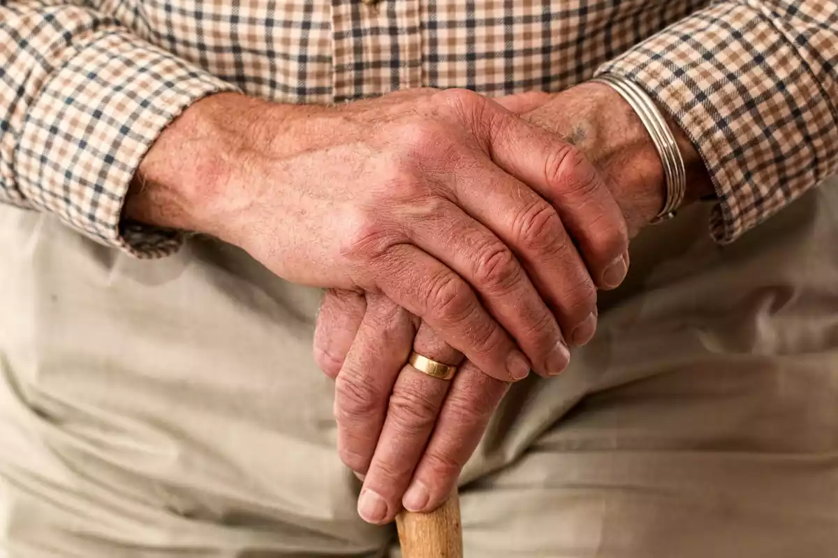 Primer plano de las manos de un abuelo sujetando un bastón