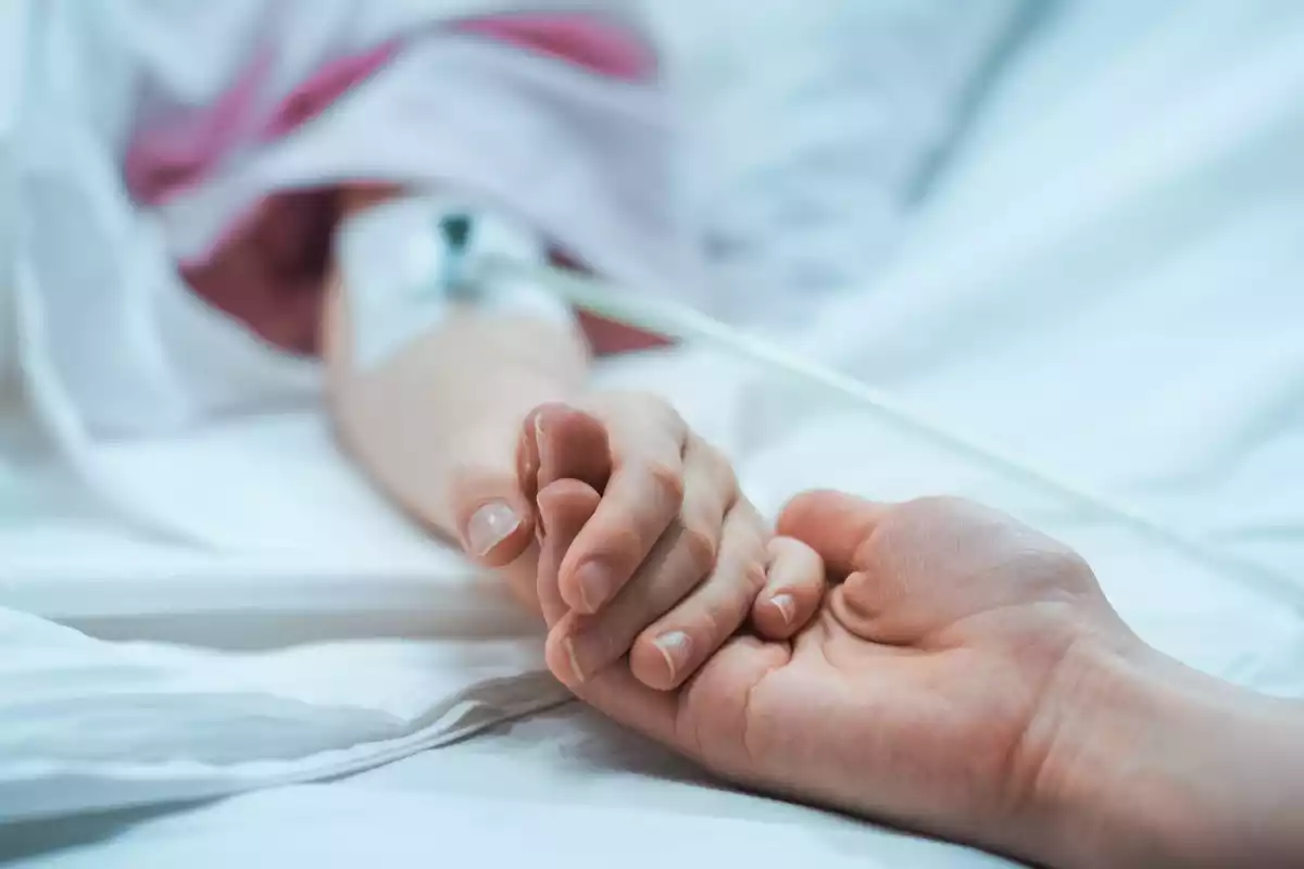 Una madre sujeta la mano de su hijo en un hospital