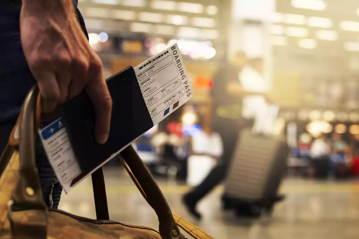 Primer plano de la mano de un hombre sujetando un billete de avión en el aeropuerto