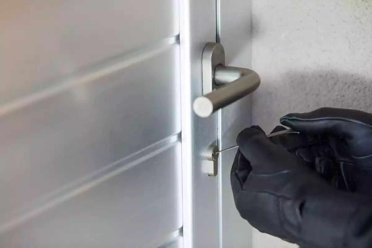 Una ladrón forzando la cerradura de una puerta