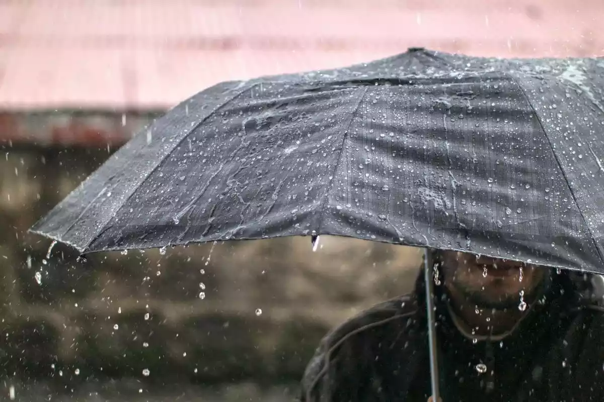Un hombre bajo un paraguas lloviendo