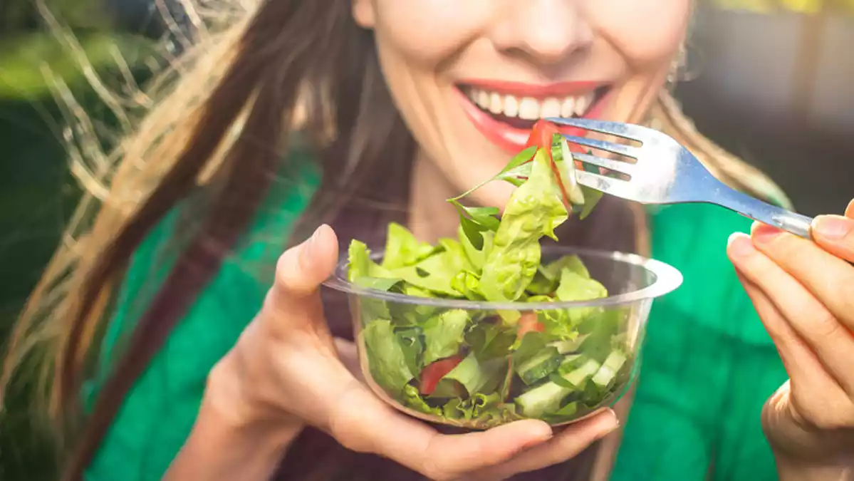 Fotografía de una mujer comiendo una ensalada